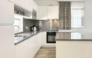 A modern kitchen with white cabinetry, a built-in oven, a coffee maker, and a microwave. - Gorgeous home in Stancija Vergotini (Stancija Vergotini)
