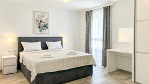 Een moderne slaapkamer met een bed, nachtkastjes, een schilderij en een bureau.