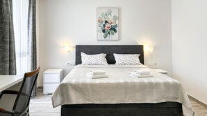 Ein Hotelzimmer mit Bett, zwei Nachttischen, einem Sessel, einem Schreibtisch und einem Bild an der Wand.
