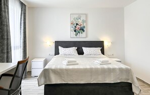 A hotel room with a bed, two nightstands, a chair, a desk, and a painting on the wall. - Stunning home in Stancija Vergotini (Stancija Vergotini)