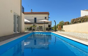 A swimming pool with lounge chairs, a building with a tiled roof, and a clear sky. - Stunning home in Stancija Vergotini (Stancija Vergotini)