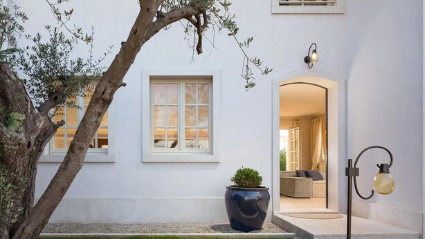 A modern building with a white exterior, a large window, a potted plant, a seating area, and a light fixture. - Luxurious home in Vabriga (Vabriga)