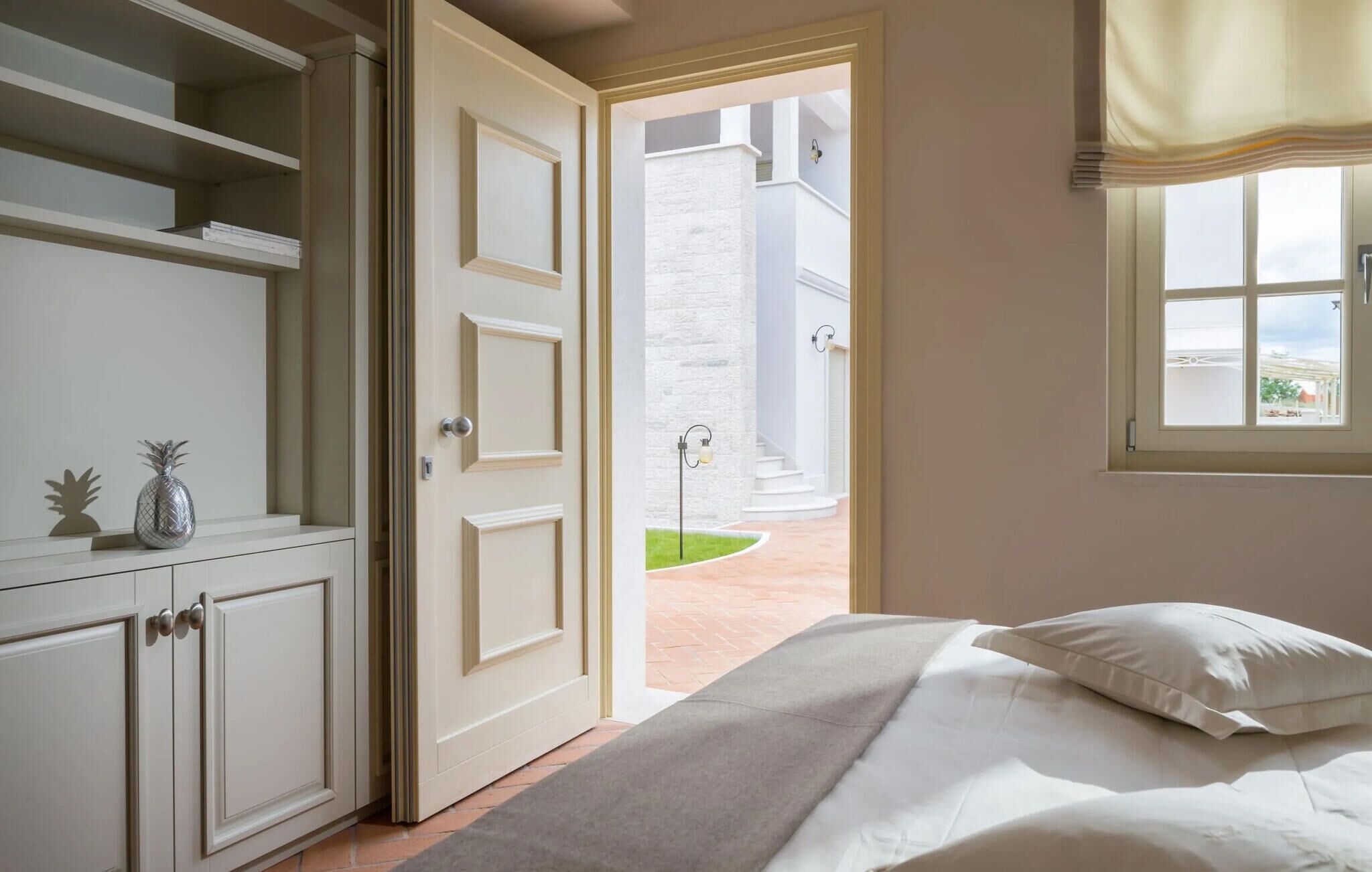 A bedroom with a bed, a wardrobe, a door leading to a balcony, and a window with curtains.