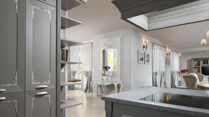 Uma cozinha moderna com armários cinza, bancada de mármore e uma janela grande com cortinas.