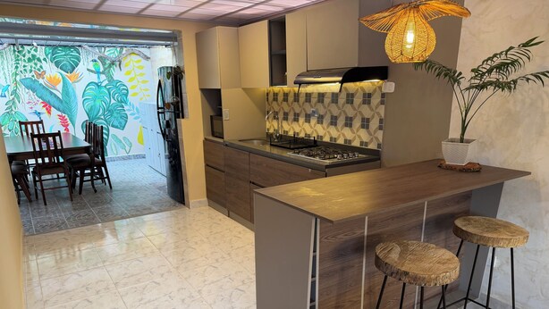 Una cocina moderna con barra, una mesa de comedor y sillas, además de un mural decorativo.