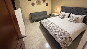 Un dormitorio con cama, sofá, mesita de noche y decoración en la pared.