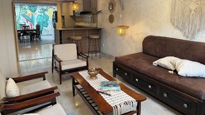 A living room with a sofa, chairs, a coffee table, and a kitchen area with stools. - Casa Danta privileged location (Salento)