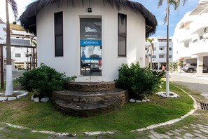 A small, white building with a thatched roof, a glass door, and a sign reading 'ACHA D'ALMA'. - Seu Lar na Praia Grande (Arraial do Cabo)