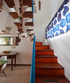 Una escalera con peldaños de madera, una pared azul de acento y utensilios de cocina colgando.