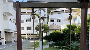 A swing set in a courtyard with a sign reading 'Villa da Praia' and modern buildings in the background. - Seu Lar na Praia Grande (Arraial do Cabo)