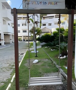 Un columpio en un patio con un letrero que dice 'Villa da Praia' y edificios modernos al fondo.