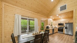 L’intérieur d’une cabane en bois comprend un coin repas, une cuisine et une fenêtre équipée de stores.