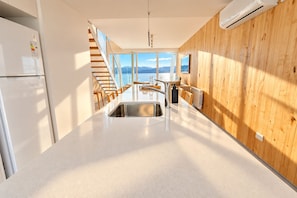Una cocina moderna con una isla central, paneles de madera en las paredes y vistas al exterior.