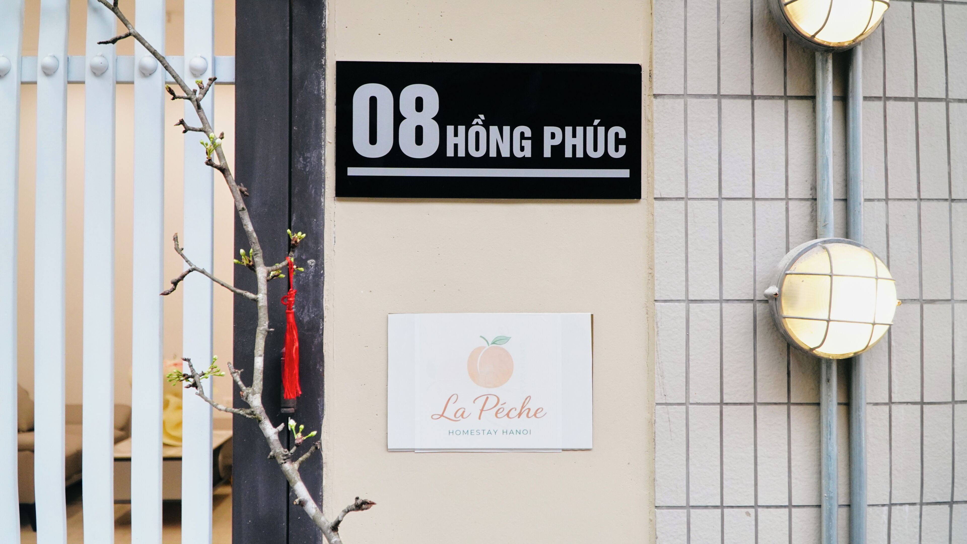 Fachada de edificio con un letrero que dice '08 HÒNG PHƯC' y un letrero más pequeño debajo que dice 'La Péche HOMESTAY HÀNÔI'.