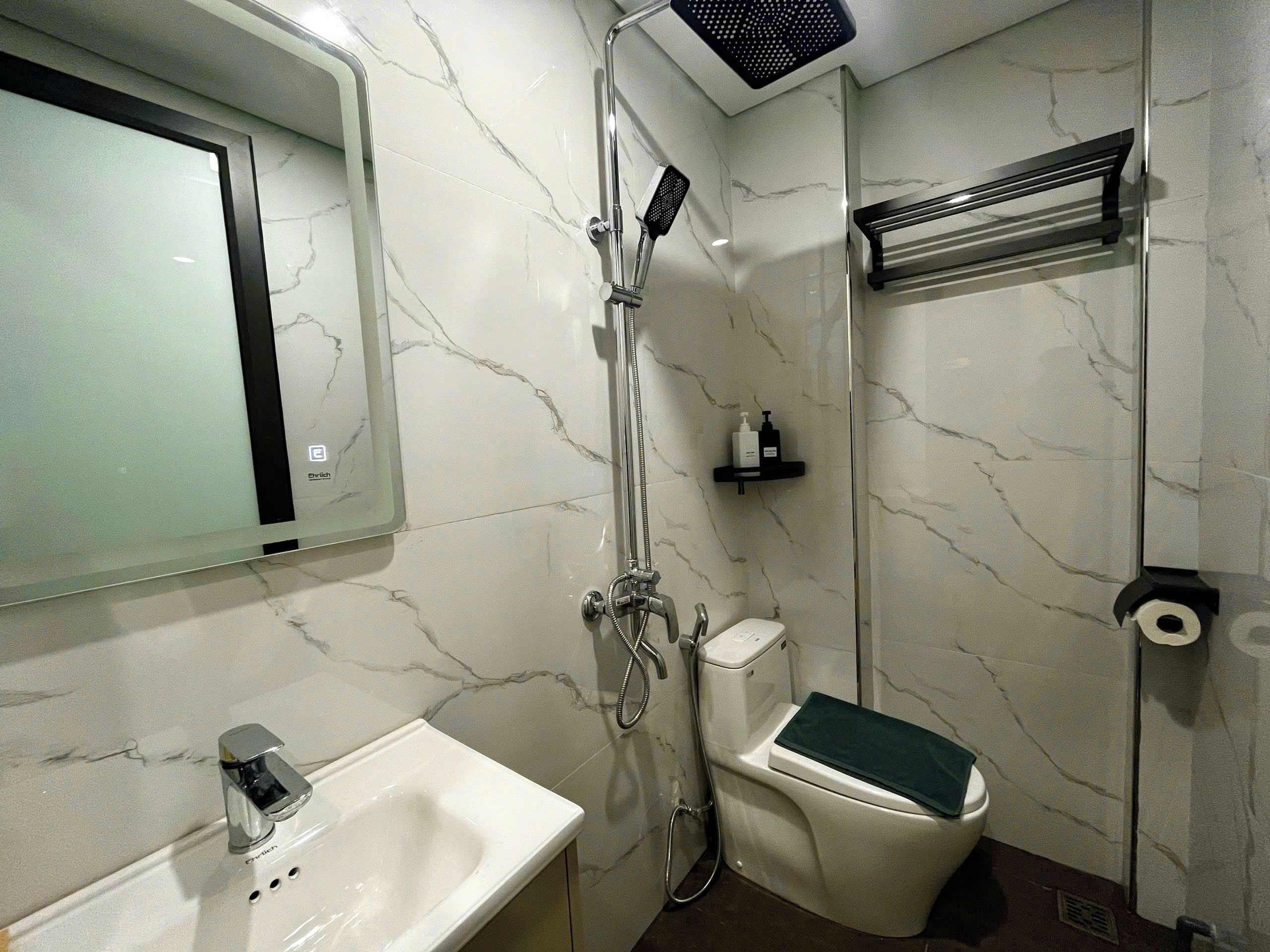 Une salle de bain équipée d’une douche, de toilettes, d’un lavabo et d’un miroir.