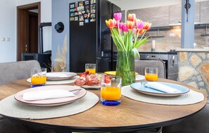 A dining table with plates, glasses, and a vase of tulips.