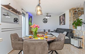 A dining area with a round table, chairs, a vase of flowers, and a clock on the wall.