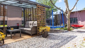 A patio with a sofa, a table, a wooden trellis, and a trampoline. - Awesome home in Jursici (Jursici)