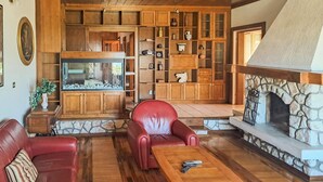Un salon chaleureux avec des meubles en bois, une cheminée en pierre et un aquarium.