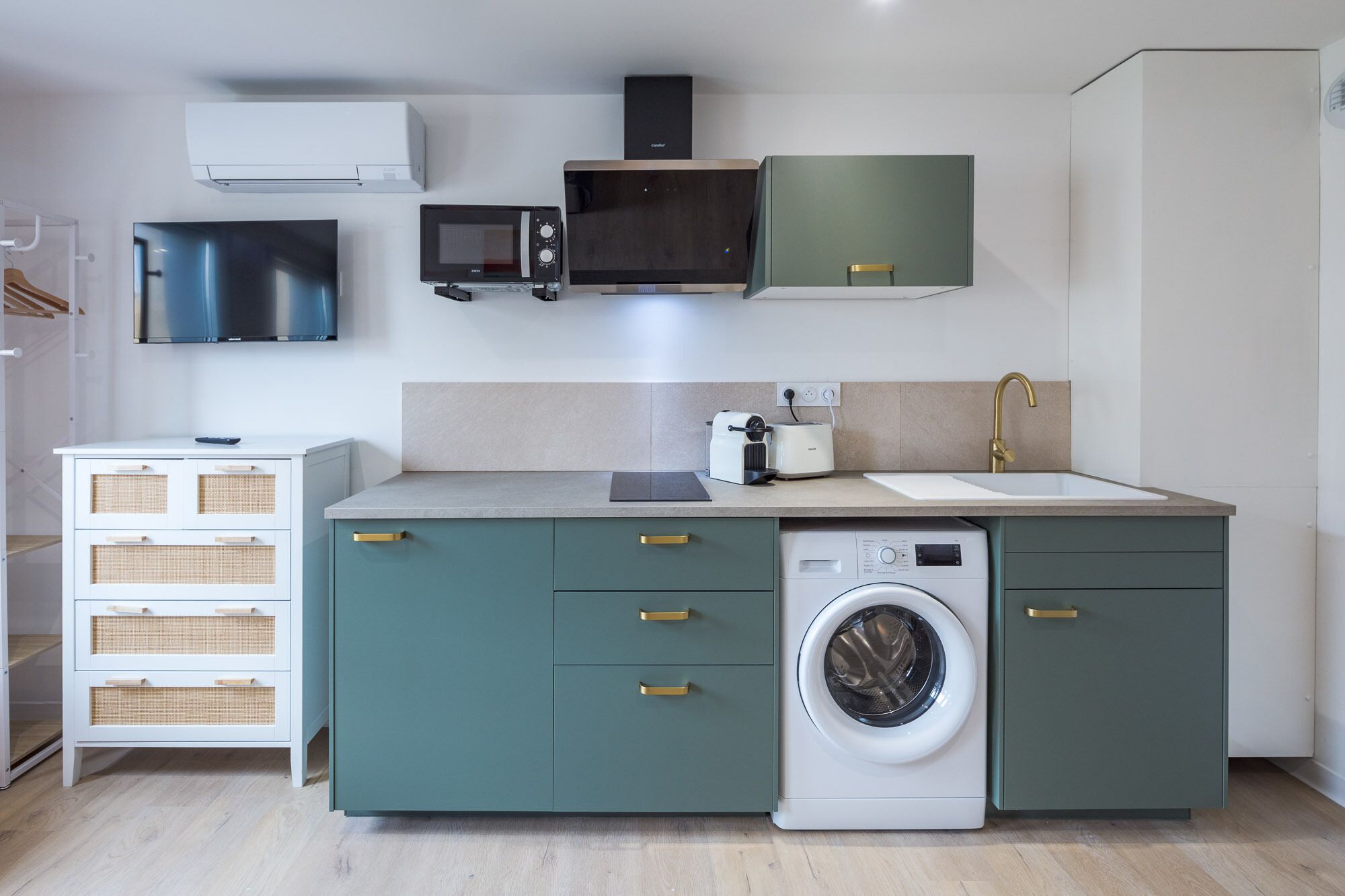 A compact kitchen with a washing machine, a microwave, a toaster, and a sink.