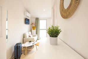A modern hotel room with a sofa, a small table, a potted plant, a suitcase, and a mirror on the wall. - Maison Flaugergues (Montpellier)