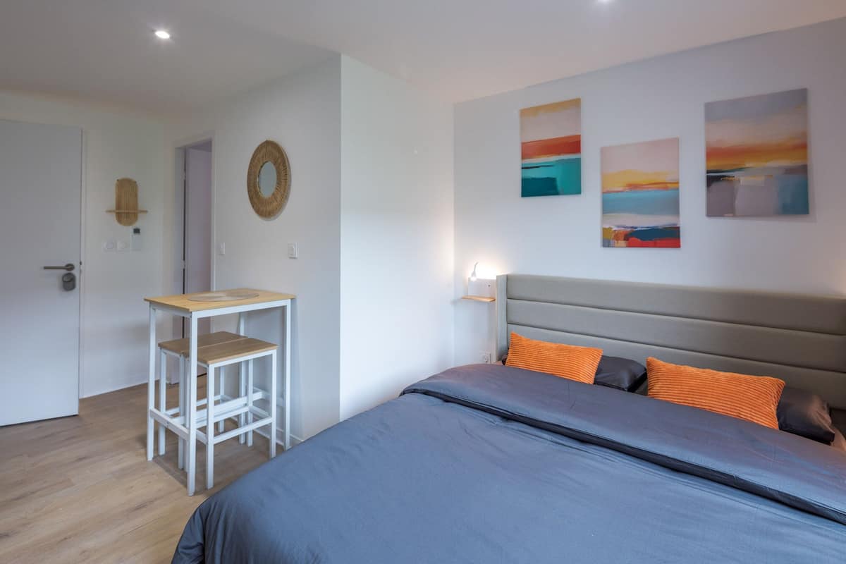 Un dormitorio con una cama, una mesita de noche, un escritorio y una pared con tres cuadros.
