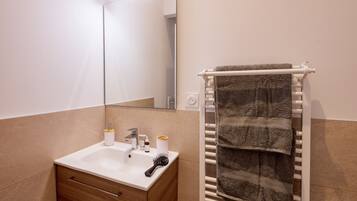 A bathroom with a sink, mirror, towel rack, and toiletries.