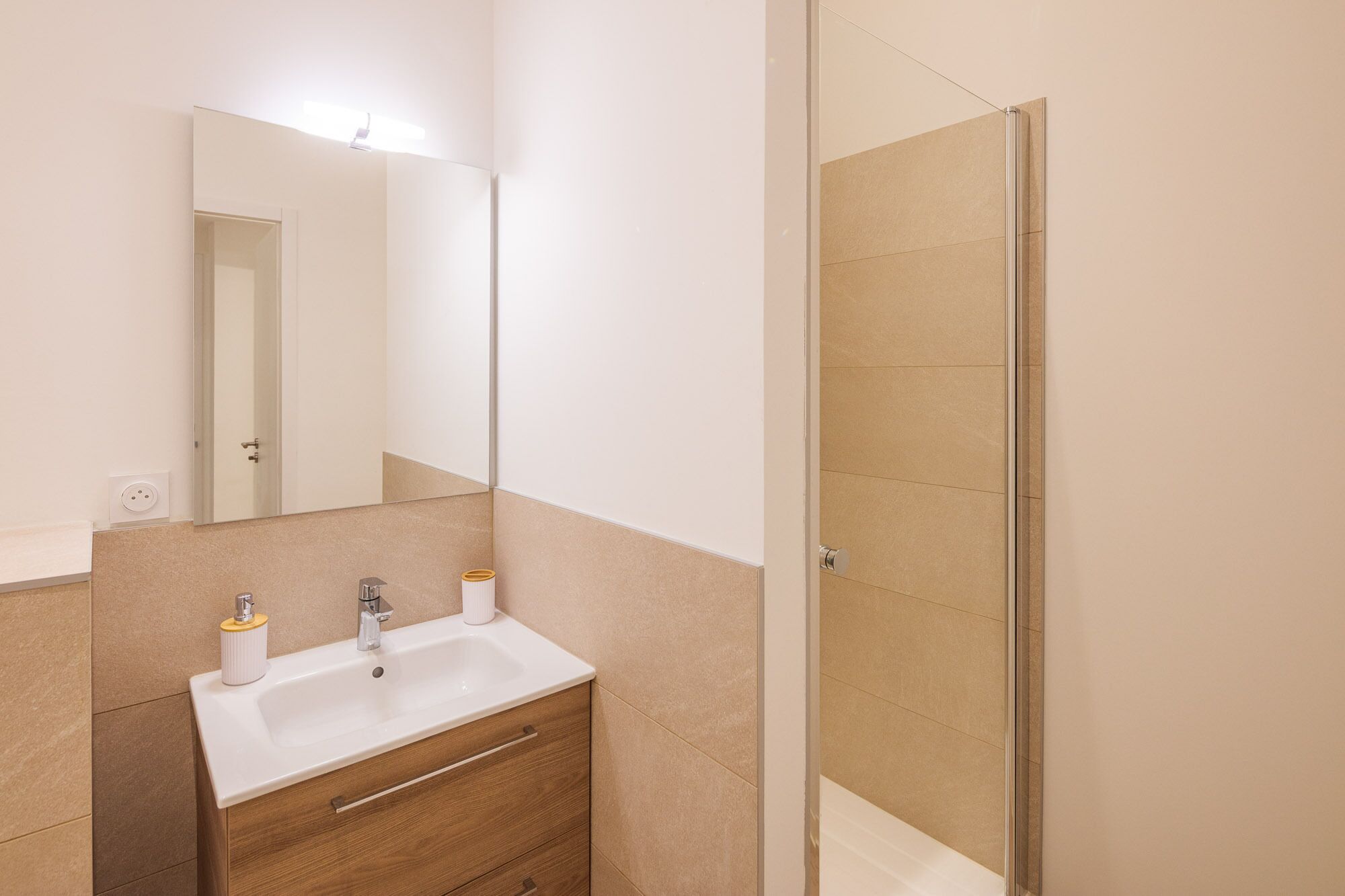 Une salle de bain avec un lavabo, un miroir et une douche.