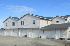 A row of single-story buildings with attached garages, under a clear sky.