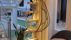 Un interior moderno con una silla colgante, escalera y plantas en macetas.