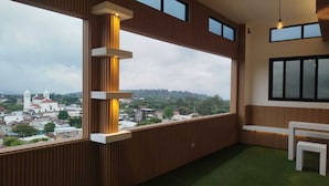 A balcony with a view of a town, a white bench, and a hanging light fixture. - height909hostal (Juayua)