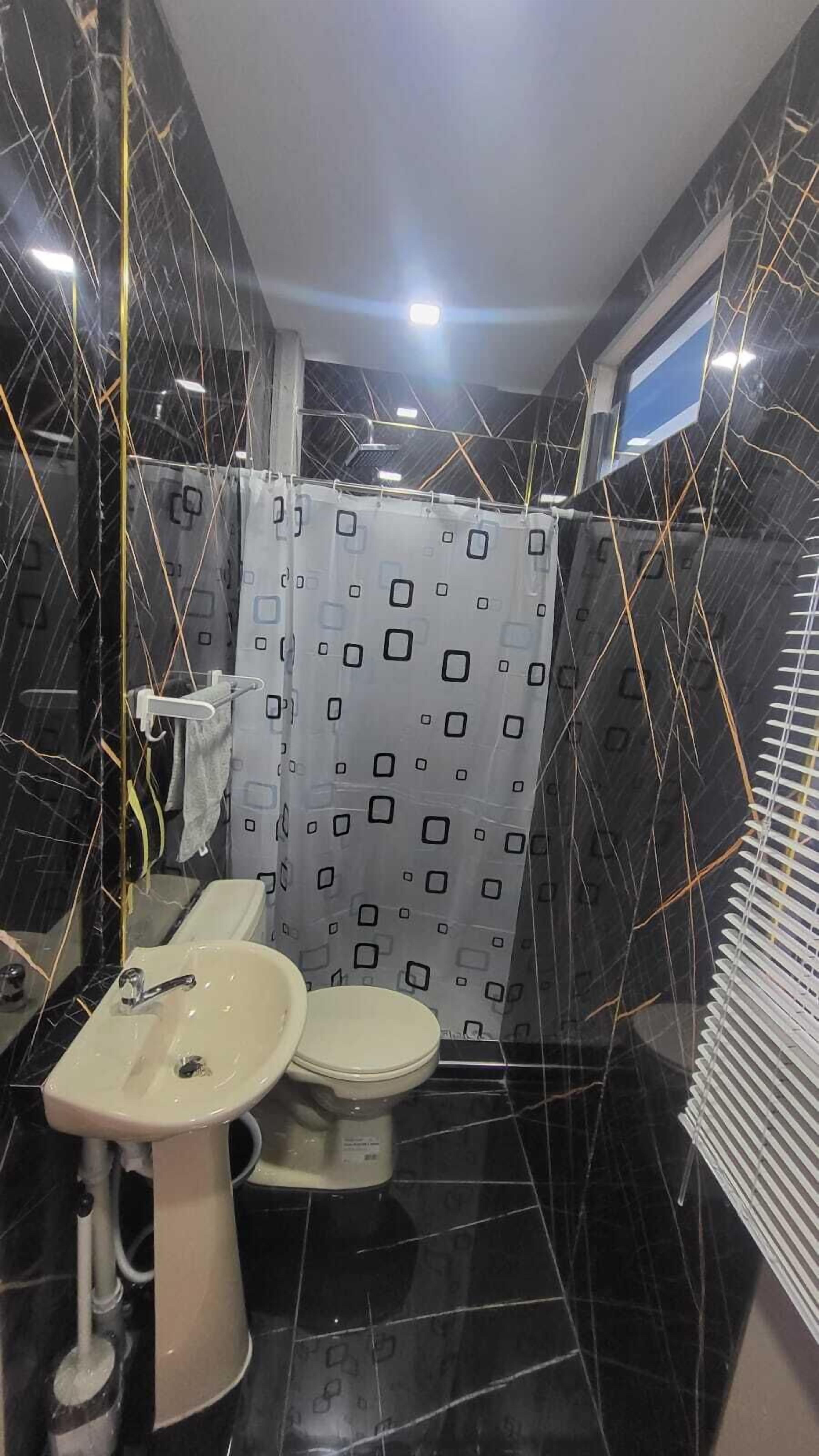A bathroom with a white sink, toilet, and shower curtain.
