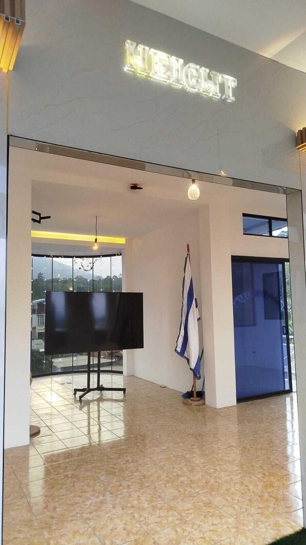 A modern interior with a large flat-screen TV, a flag, and a sign that reads 'HEIGHT.' - height909hostal (Juayua)