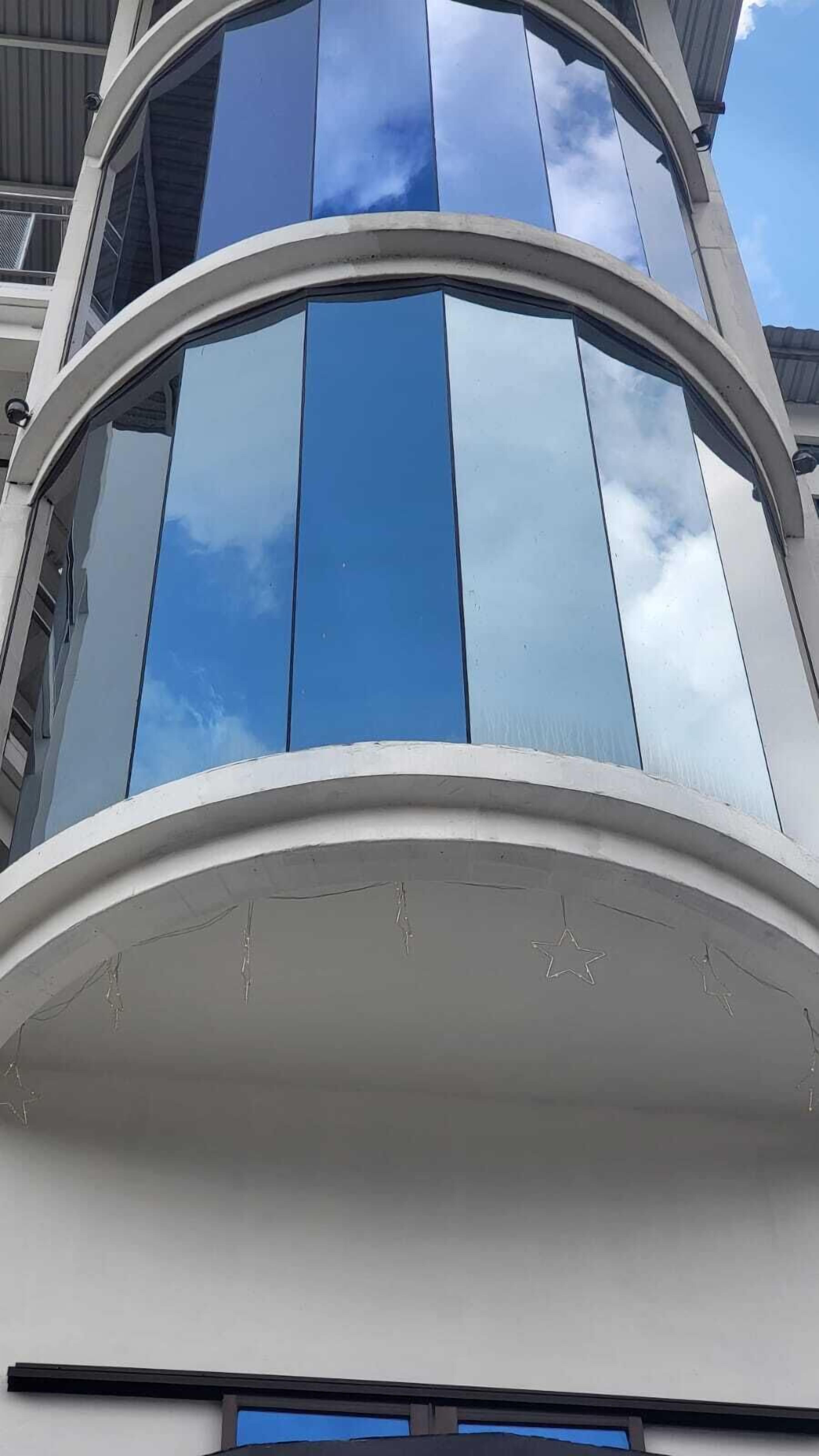 A building with a curved facade, large reflective windows, and a clear sky.