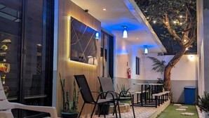 A modern outdoor patio with a dining area, chairs, and a small garden. - height909hostal (Juayua)
