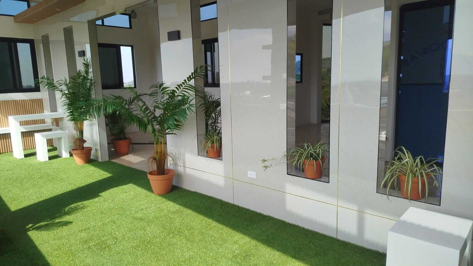 Un bâtiment moderne doté de grandes fenêtres, de plantes en pot et d’un banc blanc.
