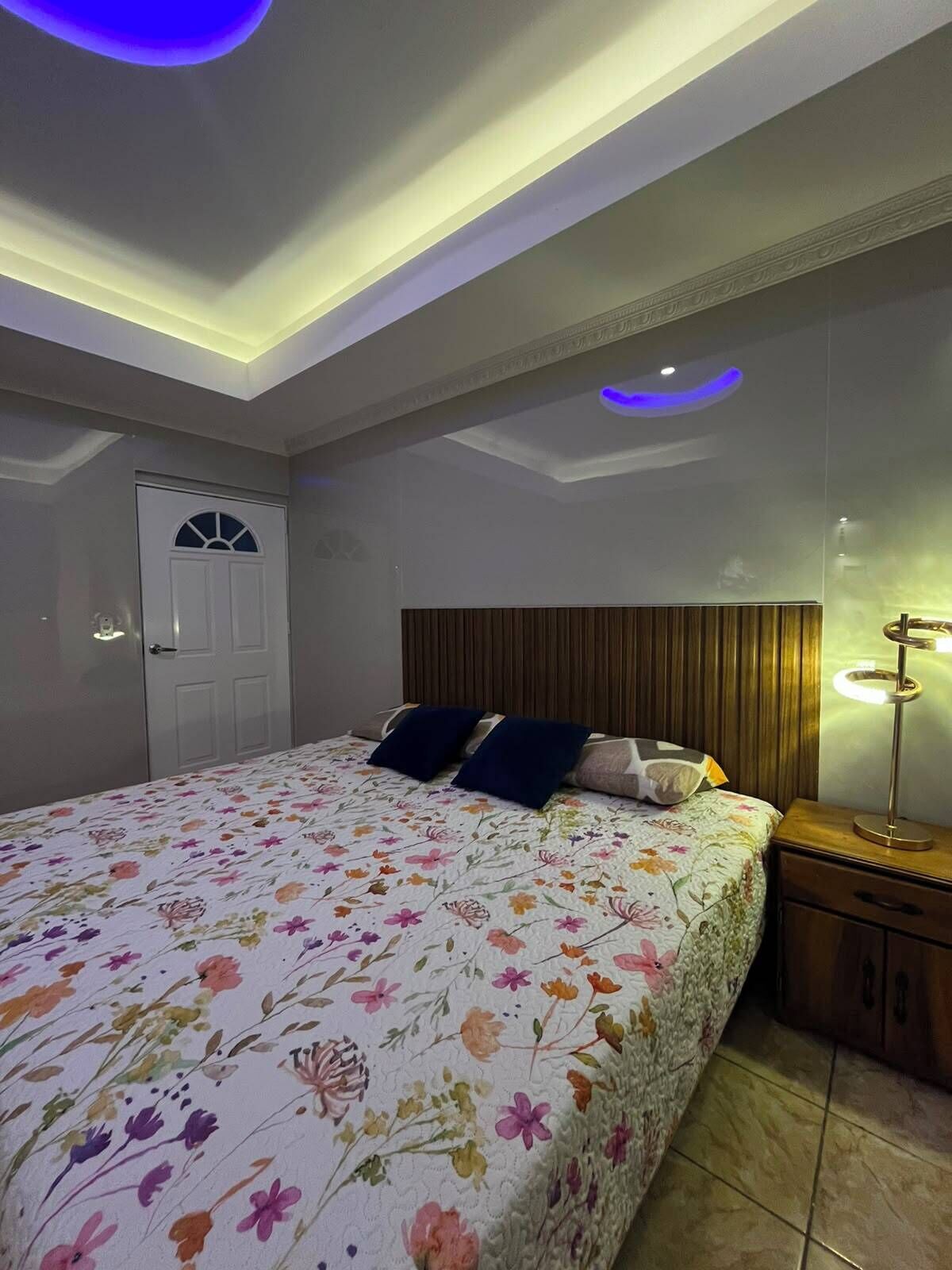 A bedroom with a bed, a nightstand, a lamp, and a door.