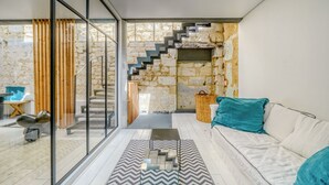 Een modern interieur met een trap, een bank en een glazen scheidingswand.