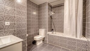 A bathroom with patterned tiles, a toilet, a sink, and a shower with a curtain. - Jardins de Flore - Studio Apartment, Sleeps 2 (Mérignac)