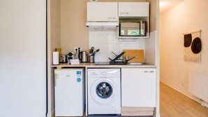 A compact kitchen with a washing machine, a microwave, and a small refrigerator. - Jardins de Flore - Studio Apartment, Sleeps 2 (Mérignac)