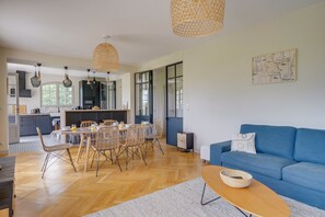 Eine moderne Küche mit Essbereich, einem blauen Sofa und einer Pendelleuchte.