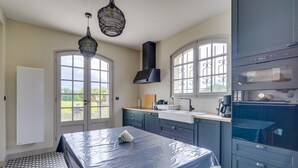 Een keuken met een groot raam, een spoelbak, een fornuis en een plafondventilator.