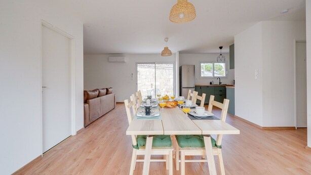 A dining area with a wooden table, chairs, and hanging lights.