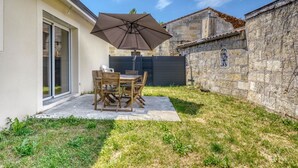 A patio with a table and chairs, an umbrella, and a stone wall.