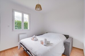 Un dormitorio con cama, mesita de noche, ventana y lámpara colgante.