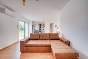 Una sala moderna con un sofá modular, un comedor y una cocina al fondo.