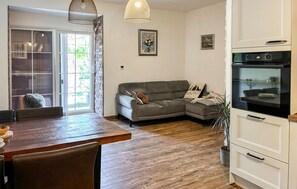 Una sala de estar con sofá, una mesa de comedor y una zona de cocina con horno.