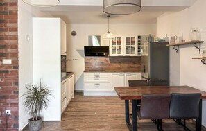 Una cocina moderna con encimeras de madera, armarios blancos y una zona de comedor con mesa y sillas.