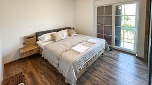 Ein Schlafzimmer mit einem Bett, einem Nachttisch, einem Deckenventilator und einem großen Fenster.