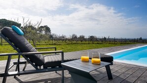 A poolside area with a lounge chair, a table with two glasses of orange juice, and a clear view of the pool and surrounding landscape. - Villa Héloïse - Three Bedroom House, Sleeps 6 (Camblanes-et-Meynac)